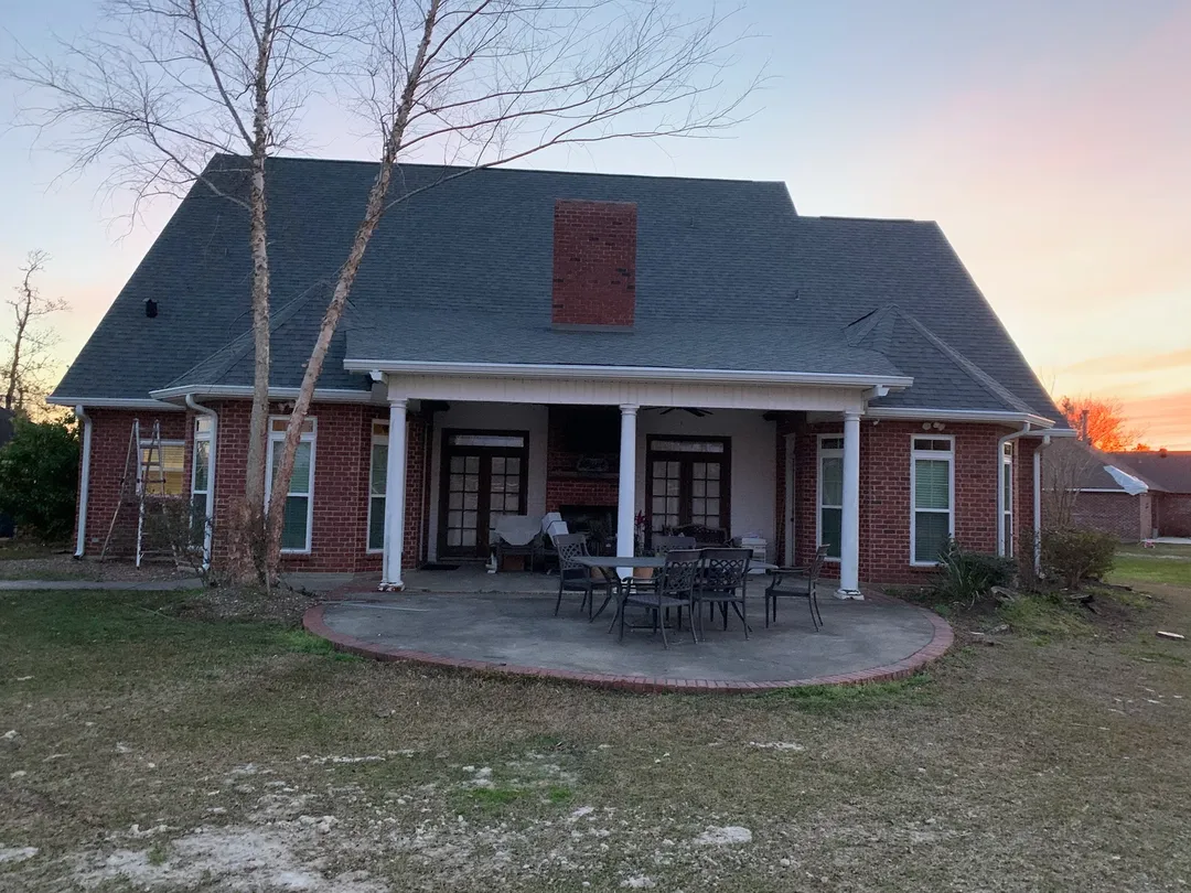 backyard view of home with white gutters and covered patio