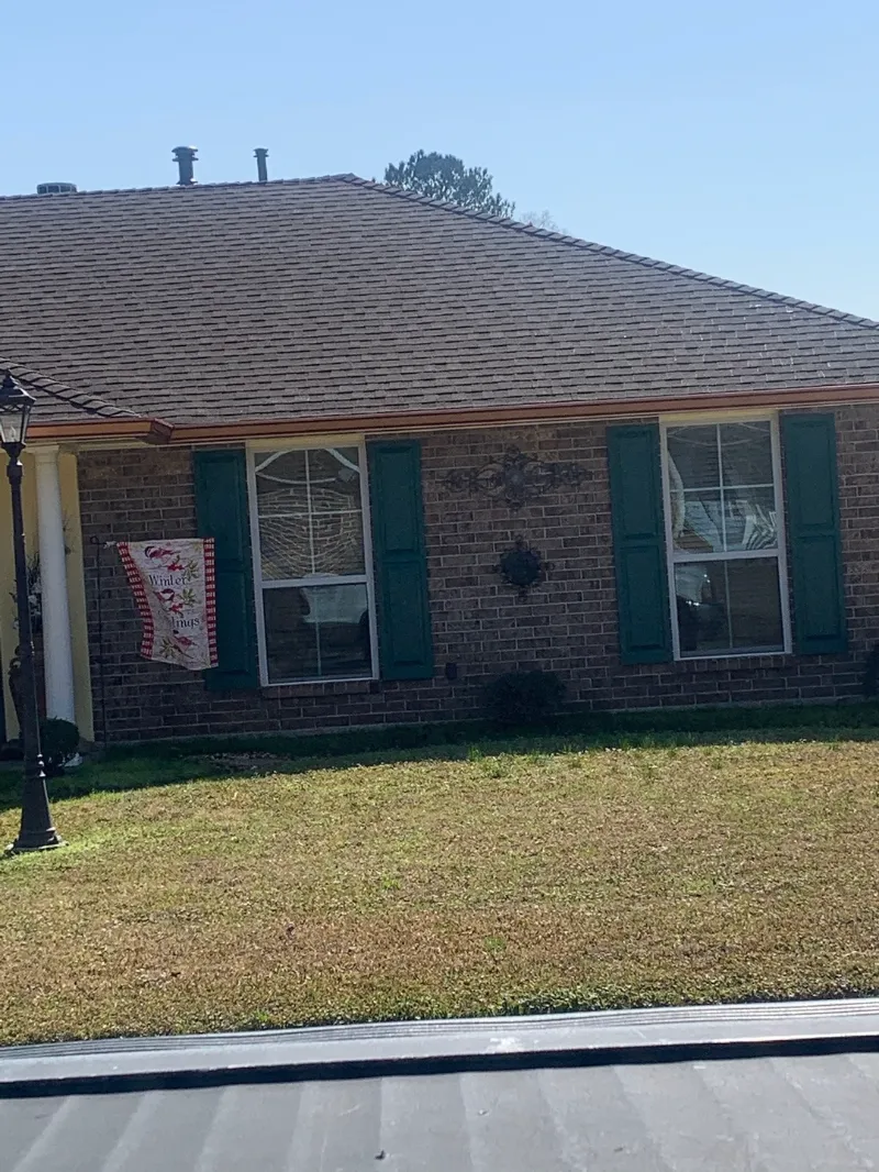 brick home green shutters holiday flag gonzales performance patios and gutters