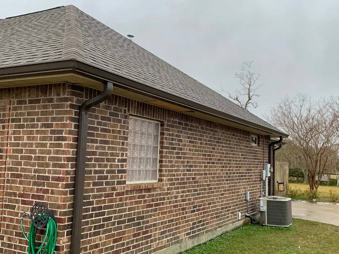 closeup of dark gutter and downspout on red brick wall