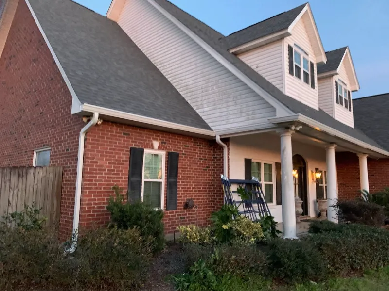 front corner of two story red brick house with whi