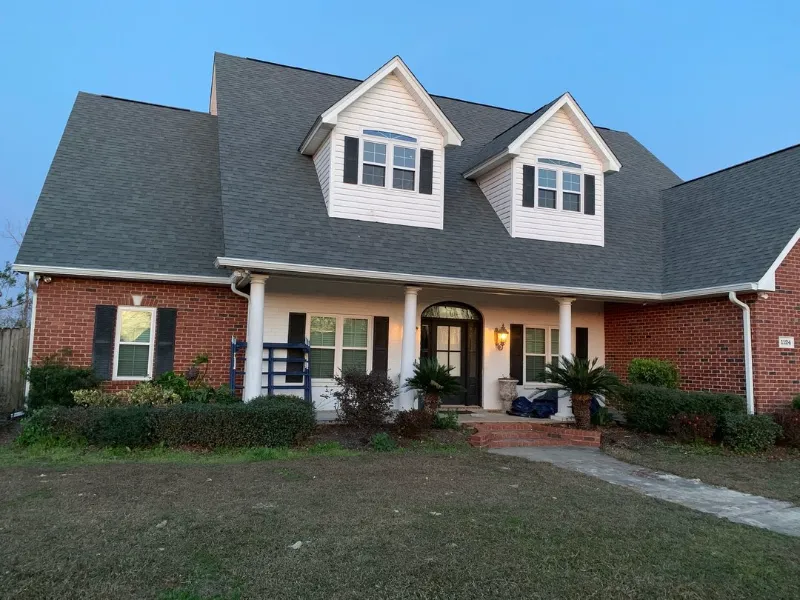 full front view of large red brick home with white