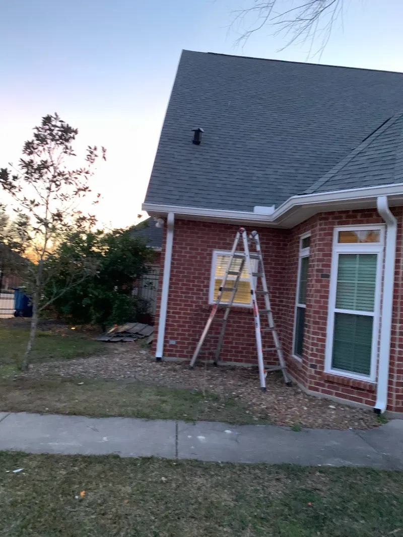 ladder in front of brick home with white gutters at sunset 1