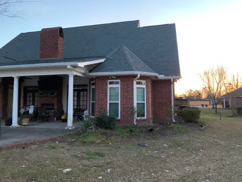 side yard view of red brick home with white gutter runoff 1