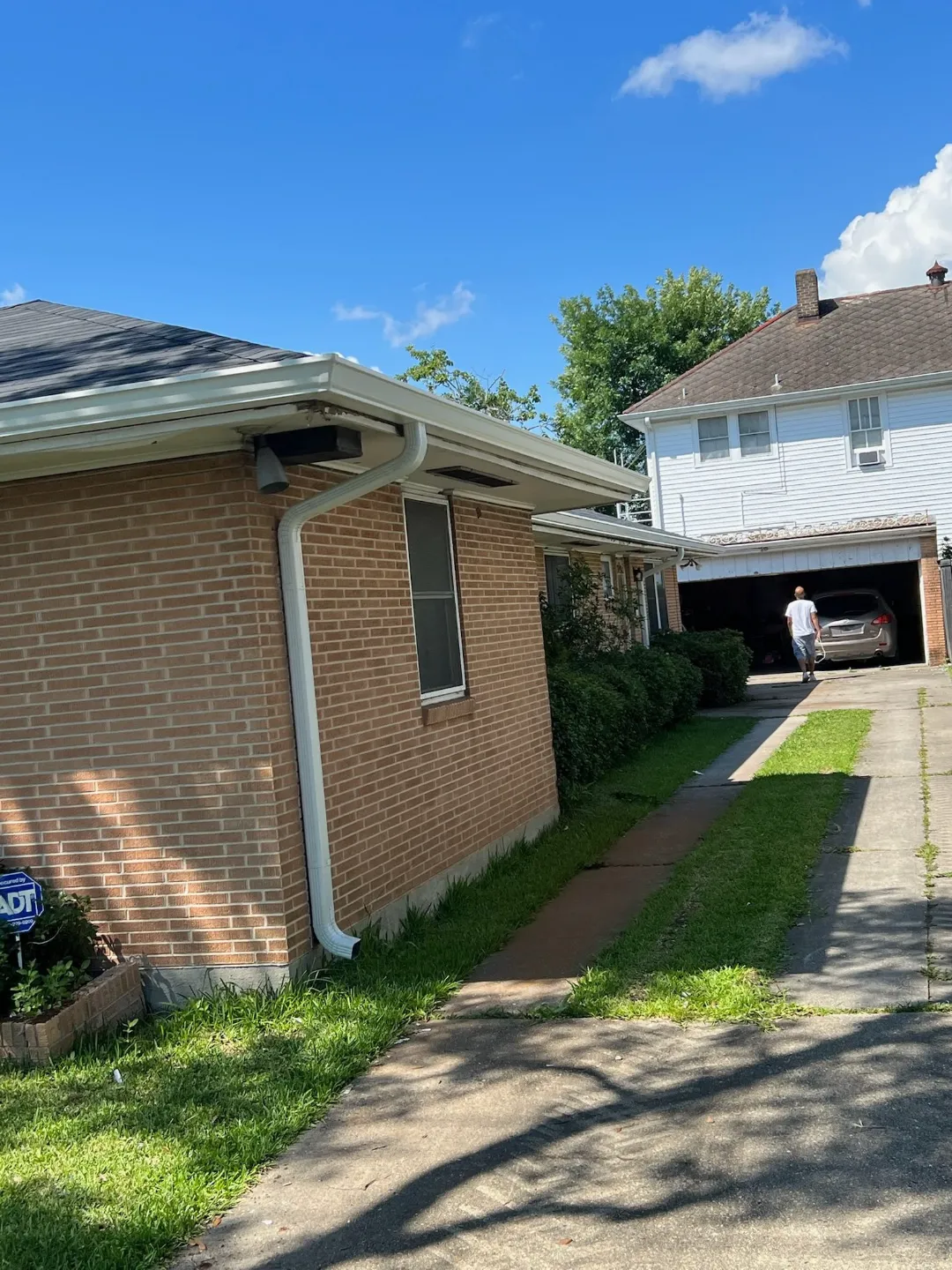 white gutters brick house driveway walker la performance patios