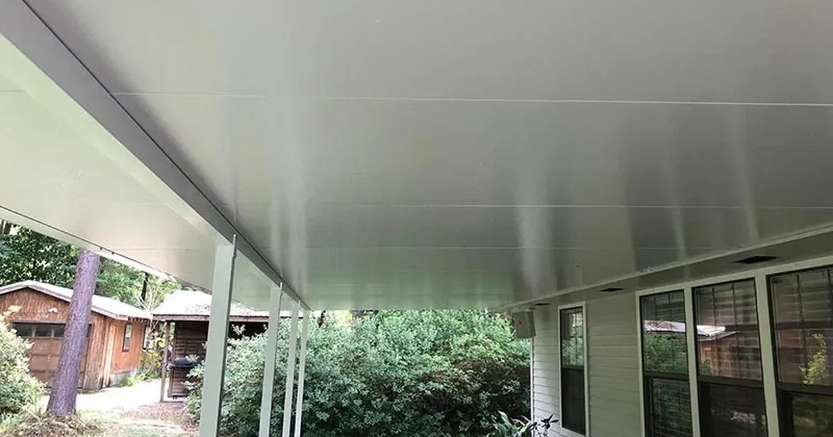 Underside of a white insulated aluminum patio cover on a Louisiana home, showing the flat finished ceiling and slim support posts.