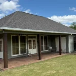 Covered patio with seamless gutters on a Louisiana home, showing the roof tie-in and support columns