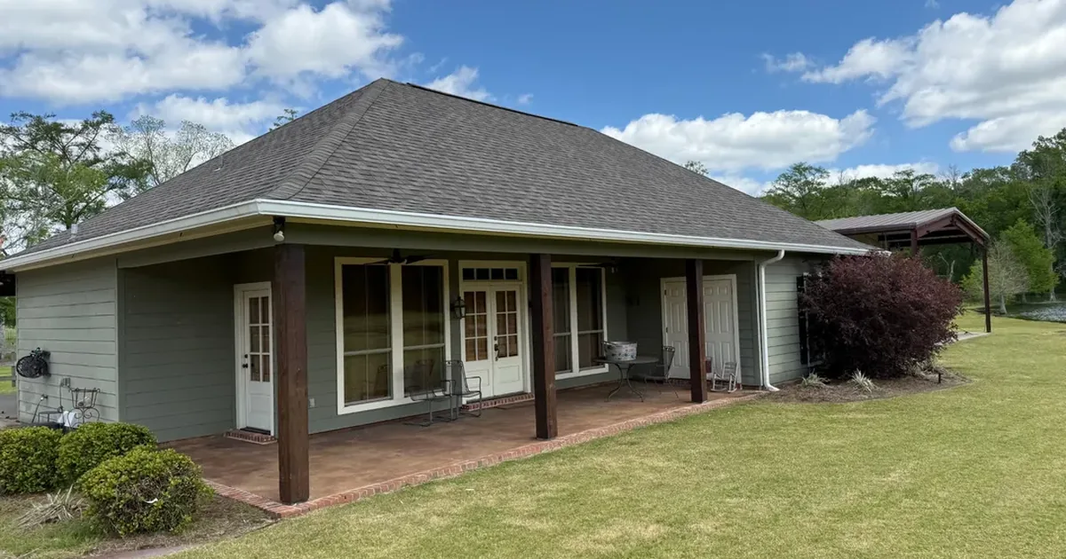 Covered patio with seamless gutters on a Louisiana home, showing the roof tie-in and support columns