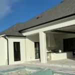 Covered outdoor living room with a new concrete deck beside a pool