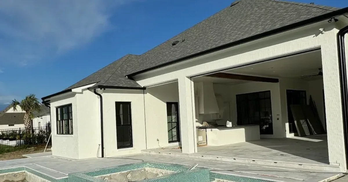 Covered outdoor living room with a new concrete deck beside a pool
