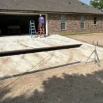 Prepared concrete slab with a screed board and laser level at a brick home