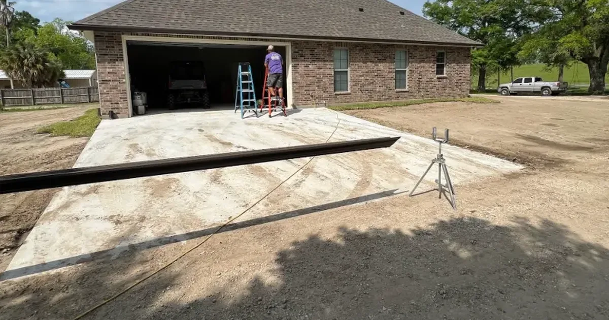 Prepared concrete slab with a screed board and laser level at a brick home