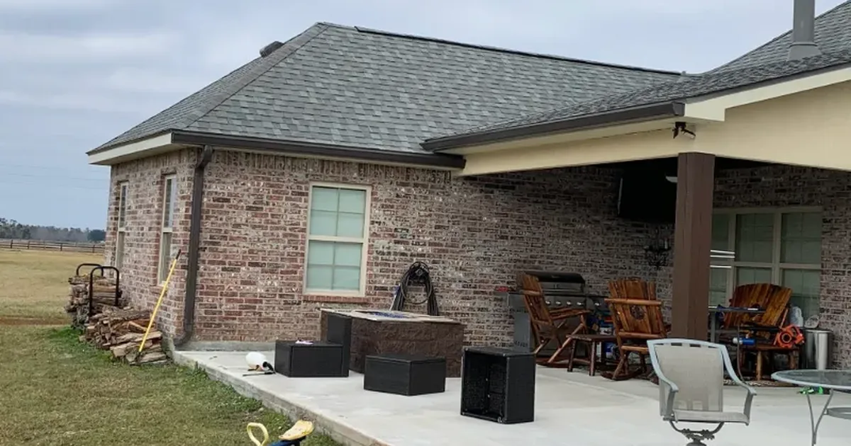Covered patio attached to a brick home under a gray sky